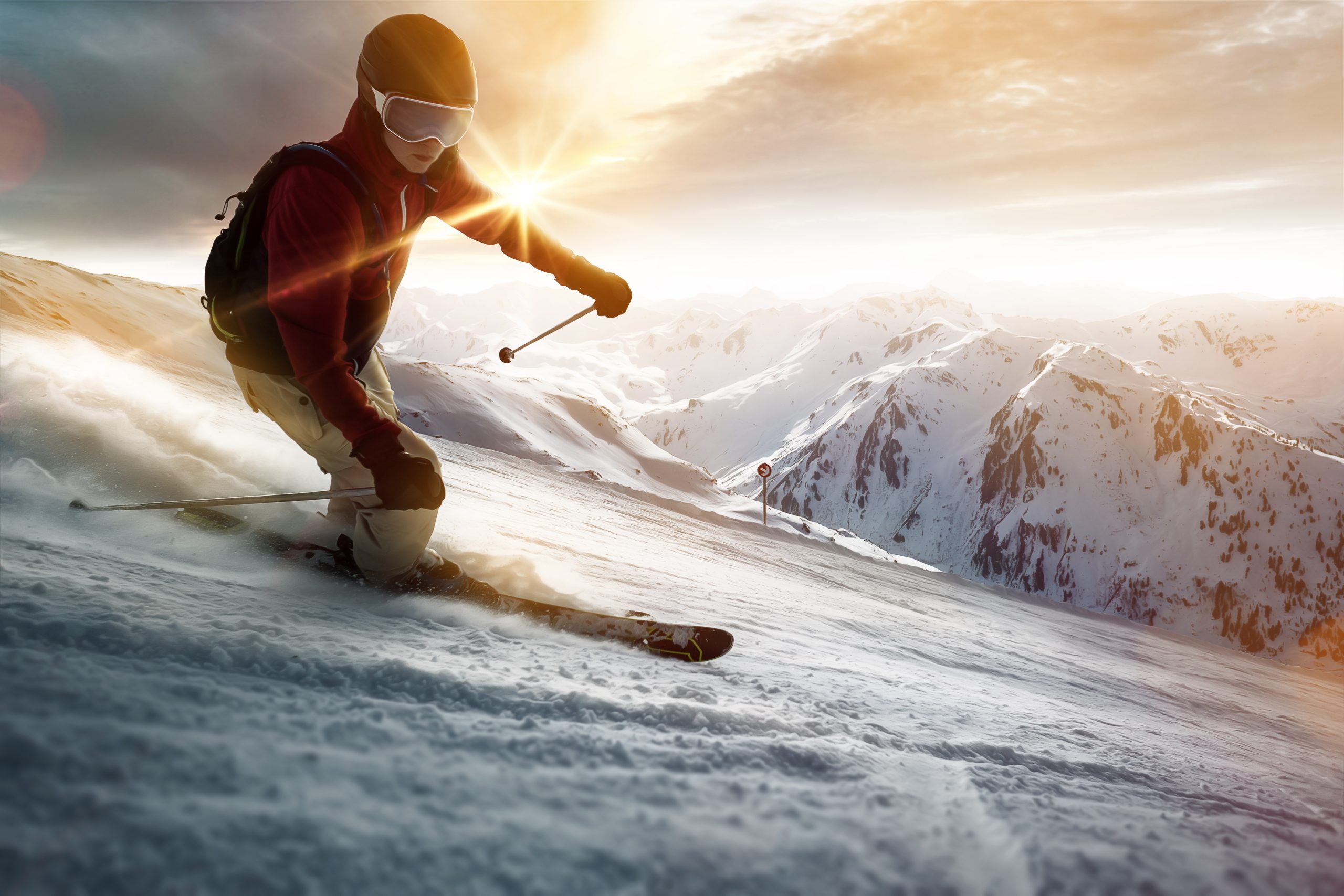 Skifahrer, der bei Sonnenuntergang gerade eine Piste hinunter fährt