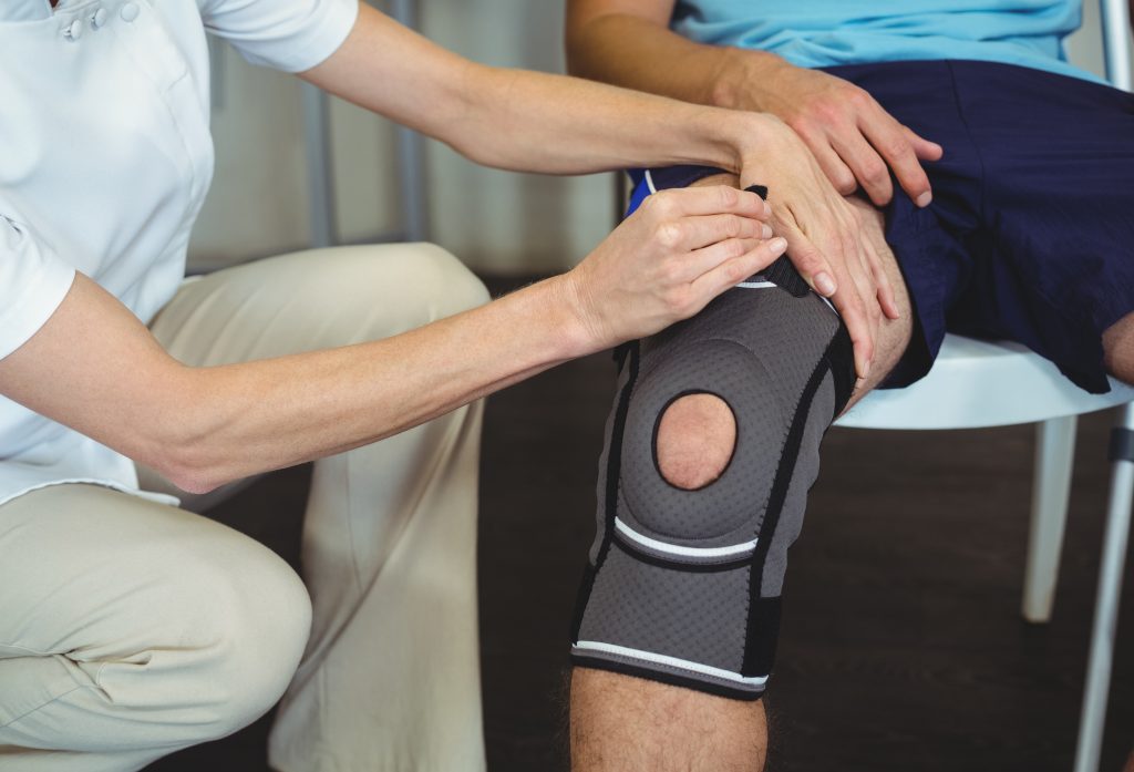 Physiotherapeutin untersucht das Knie eines Patienten