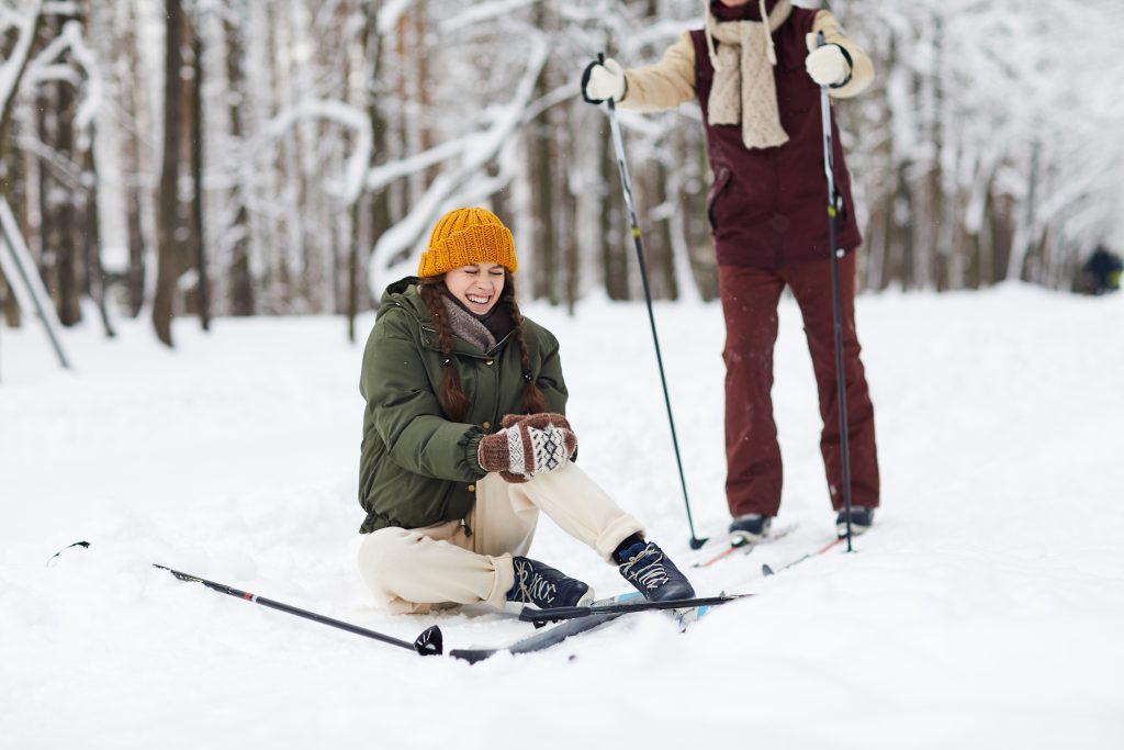 Frau, die sich beim Skifahren das Knie verletzt hat